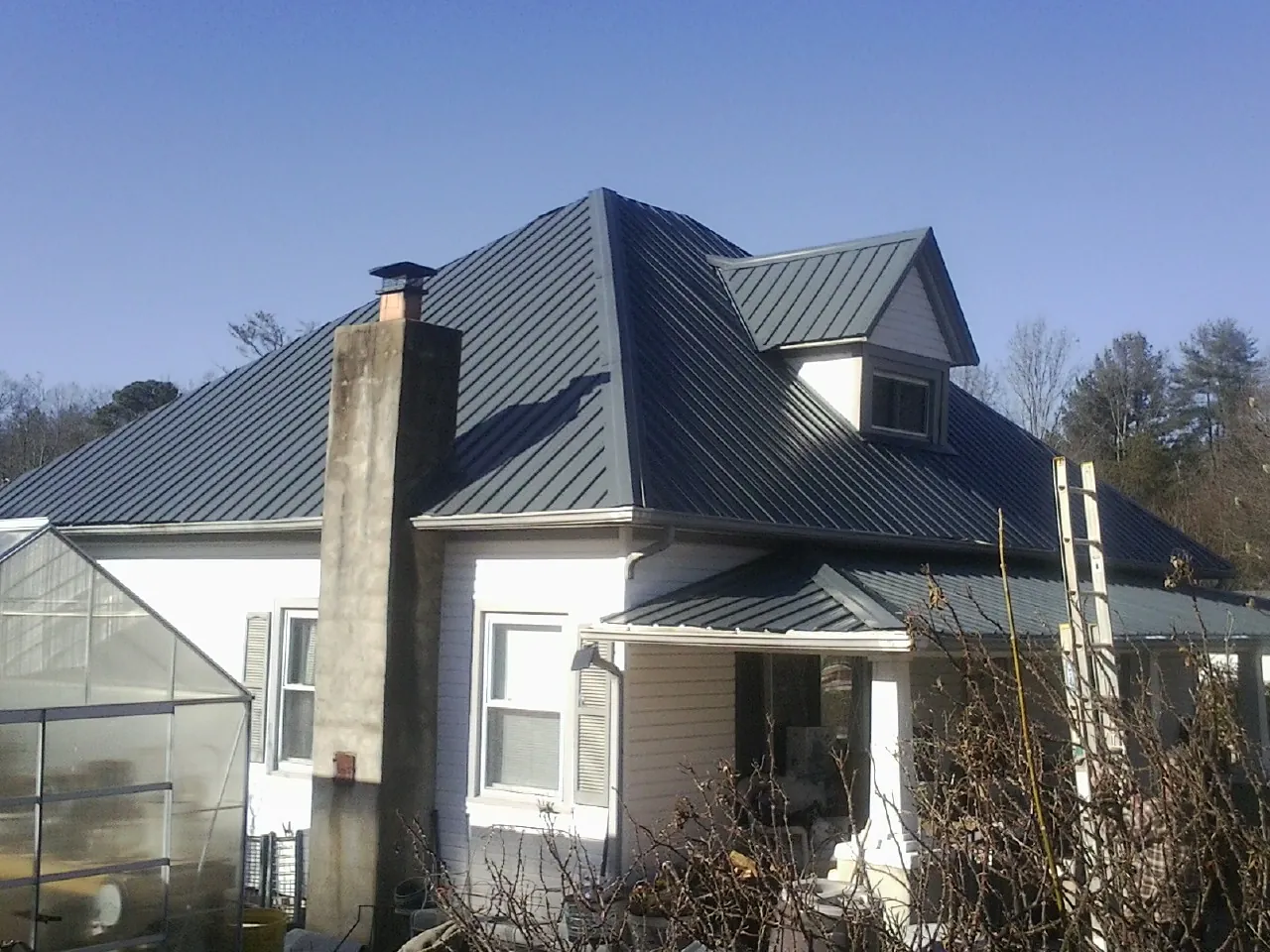 Dark blue standing seam metal roof on a white farmhouse with dormer — Slate & Tile Roof Repair by Roofing Brothers in Coolville