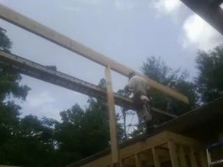 Carpenter setting a ridge beam over a new addition frame — Ice Dam Removal by Roofing Brothers in Coolville