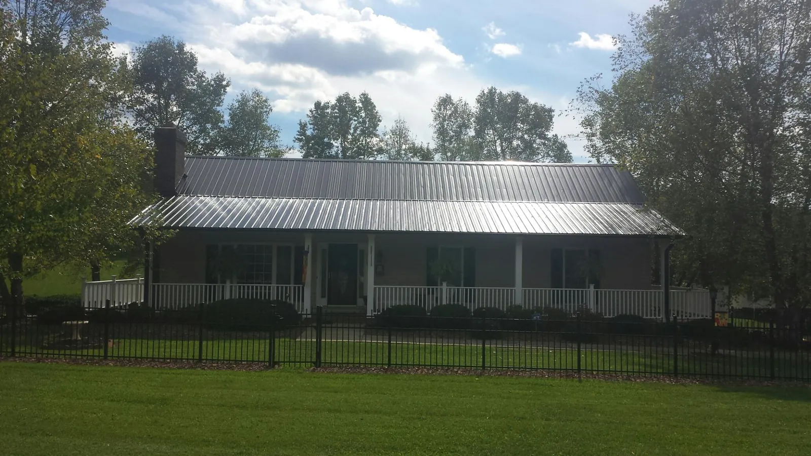 Gray metal roof on a brick ranch with a full width front porch — Gutter Guard Installation work by our crew in Coolville
