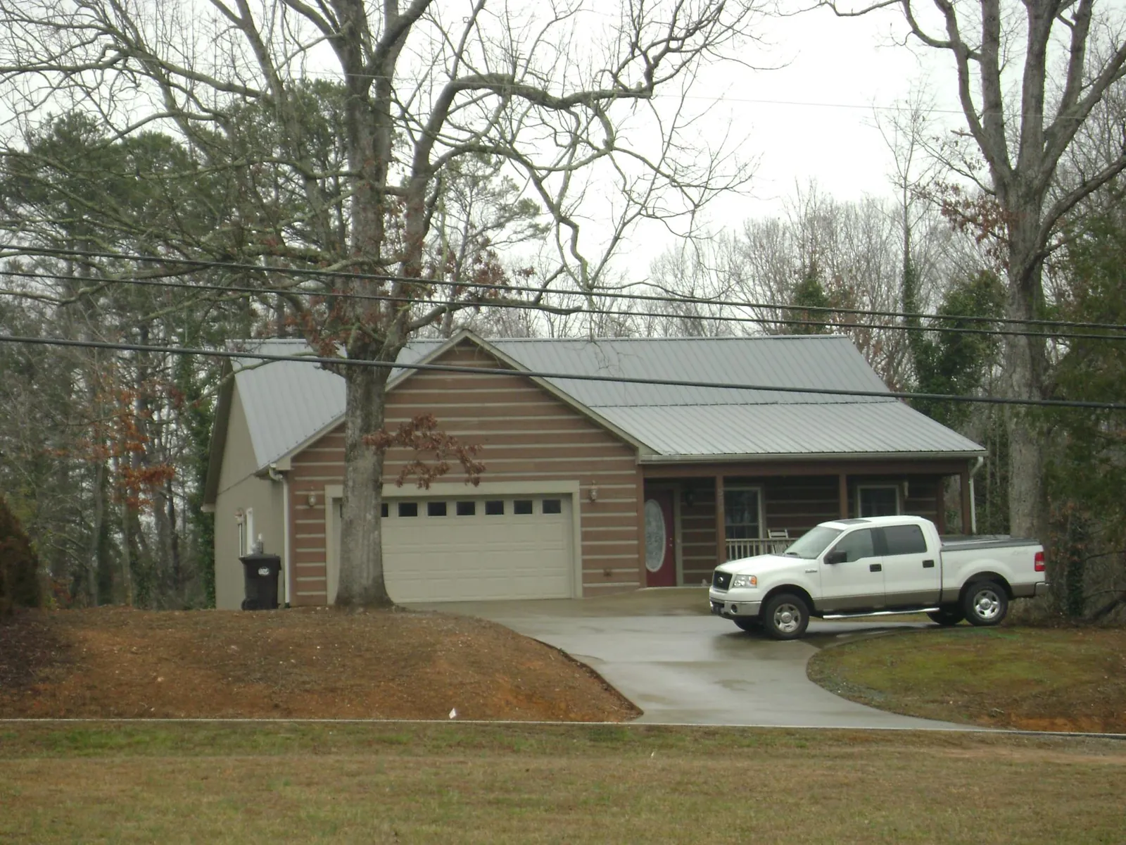 Gray metal roof on a log sided house with an attached two car garage in Coolville