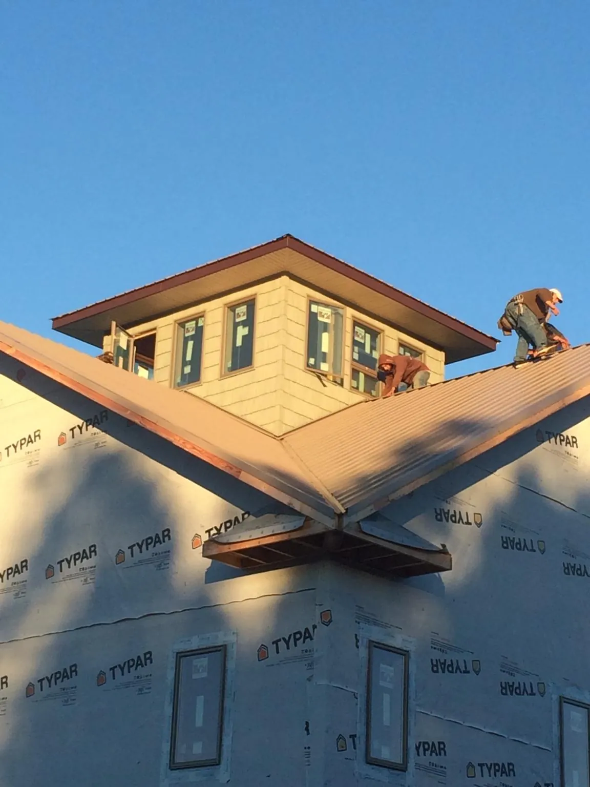 Roofers working around a rooftop cupola on a new metal roof at sunset — Roof Waterproofing in Coolville by Roofing Brothers